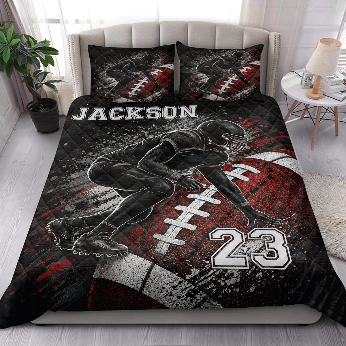 Football quilt blanket styled on a bedroom bed with dramatic black, red, and white artwork