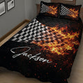 Black racing quilt blanket with fiery checkered flag artwork draped across a bed