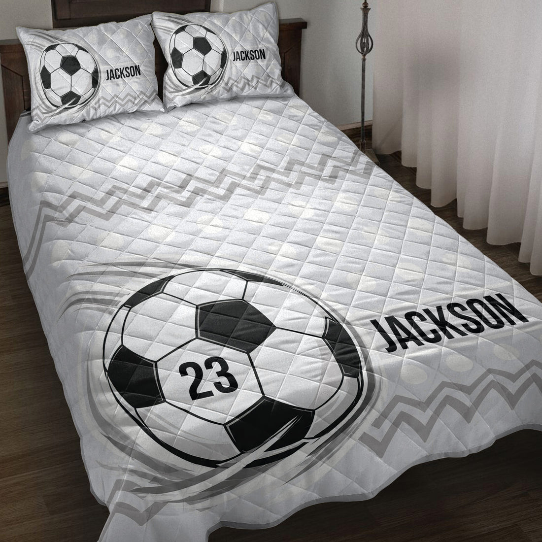 Soccer quilt blanket displayed on a bed with black and white ball artwork and geometric accents