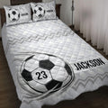 Soccer quilt blanket displayed on a bed with black and white ball artwork and geometric accents