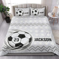 Soccer quilt bedding styled in a bright bedroom with ball artwork and black and white geometric details