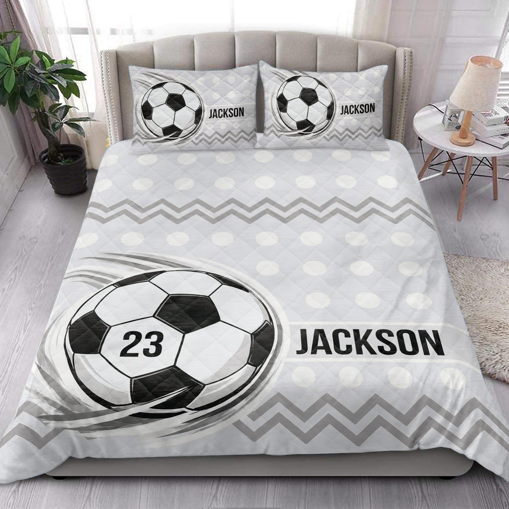 Soccer quilt bedding styled in a bright bedroom with ball artwork and black and white geometric details