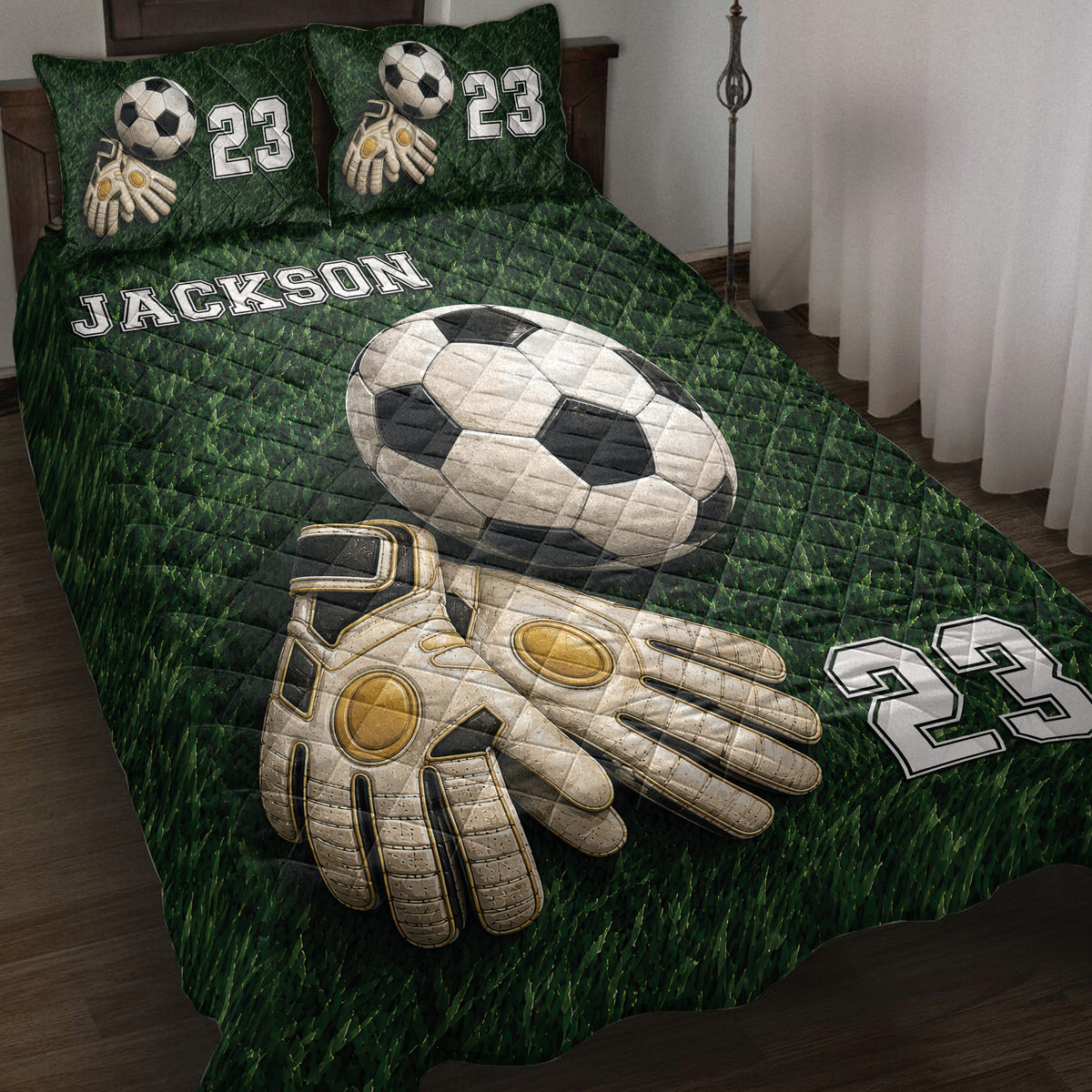 Soccer quilt blanket displayed on a bed with goalkeeper gloves, soccer ball artwork, and green field design