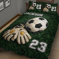 Close view of soccer quilt bedding with goalkeeper gloves, soccer ball artwork, and green grass background