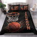 Basketball quilt blanket styled on a bed in a bright bedroom with black and orange sports artwork
