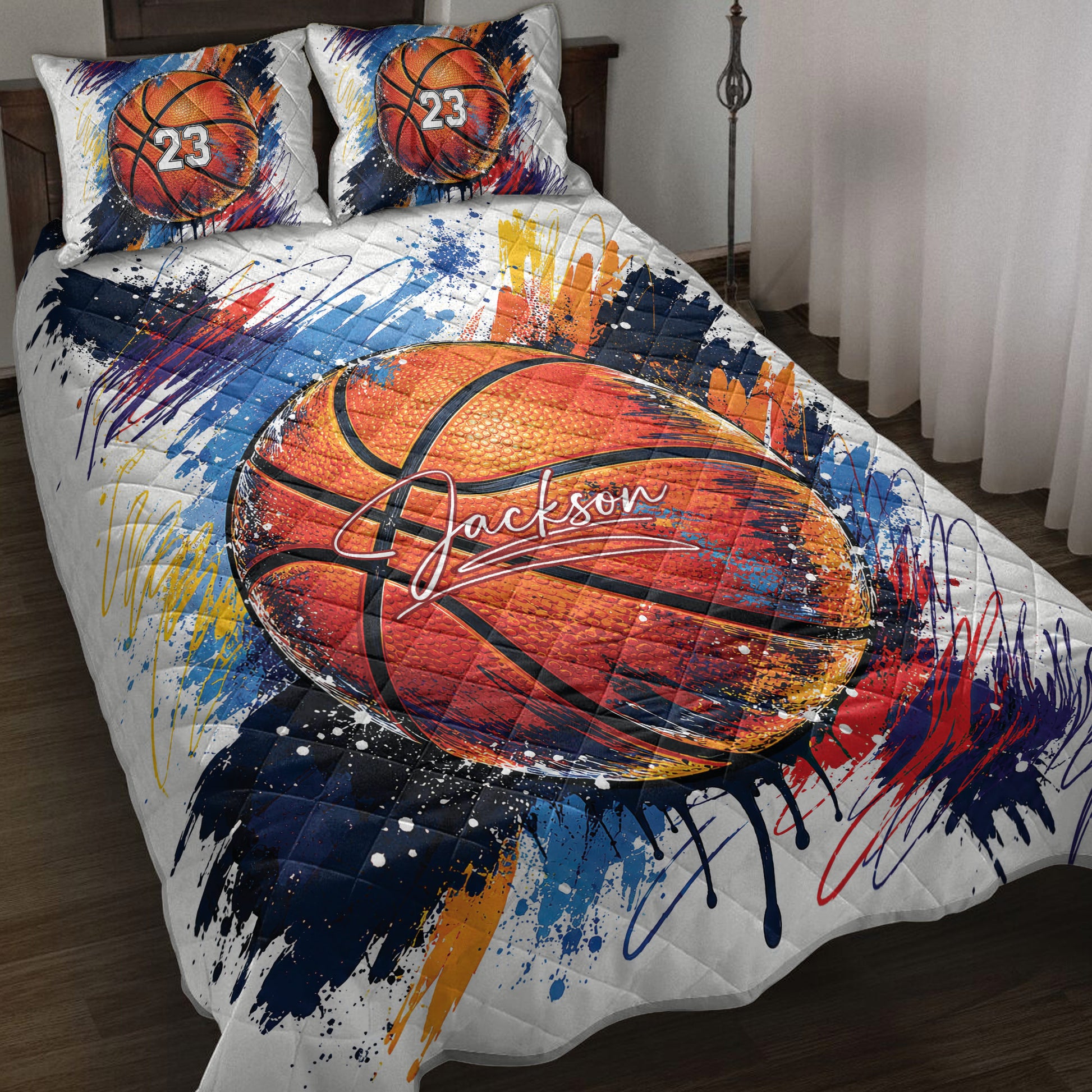 Basketball quilt blanket on a bed with vibrant orange, blue, red, and yellow paint-splatter artwork