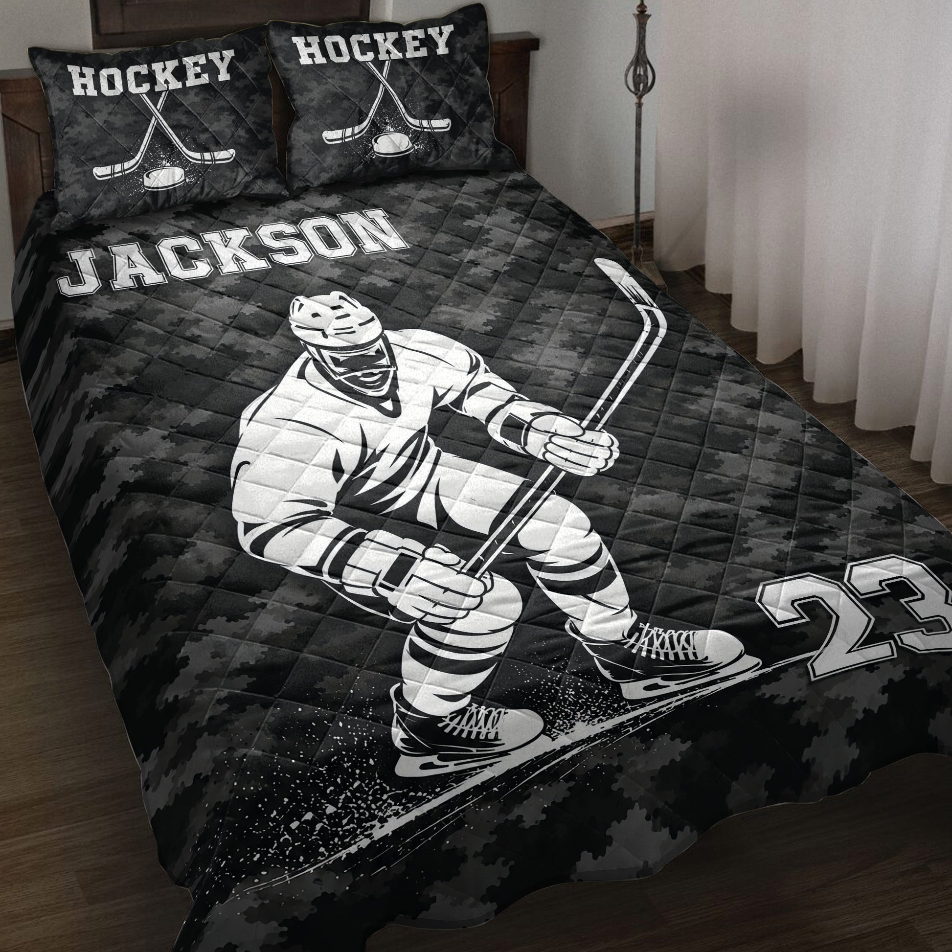 Black hockey quilt blanket displayed on a bed with a hockey player, crossed sticks, puck, skates, and bold sports artwork