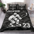 Hockey quilt blanket styled on a bedroom bed with a skating player, hockey sticks, puck, and bold monochrome artwork
