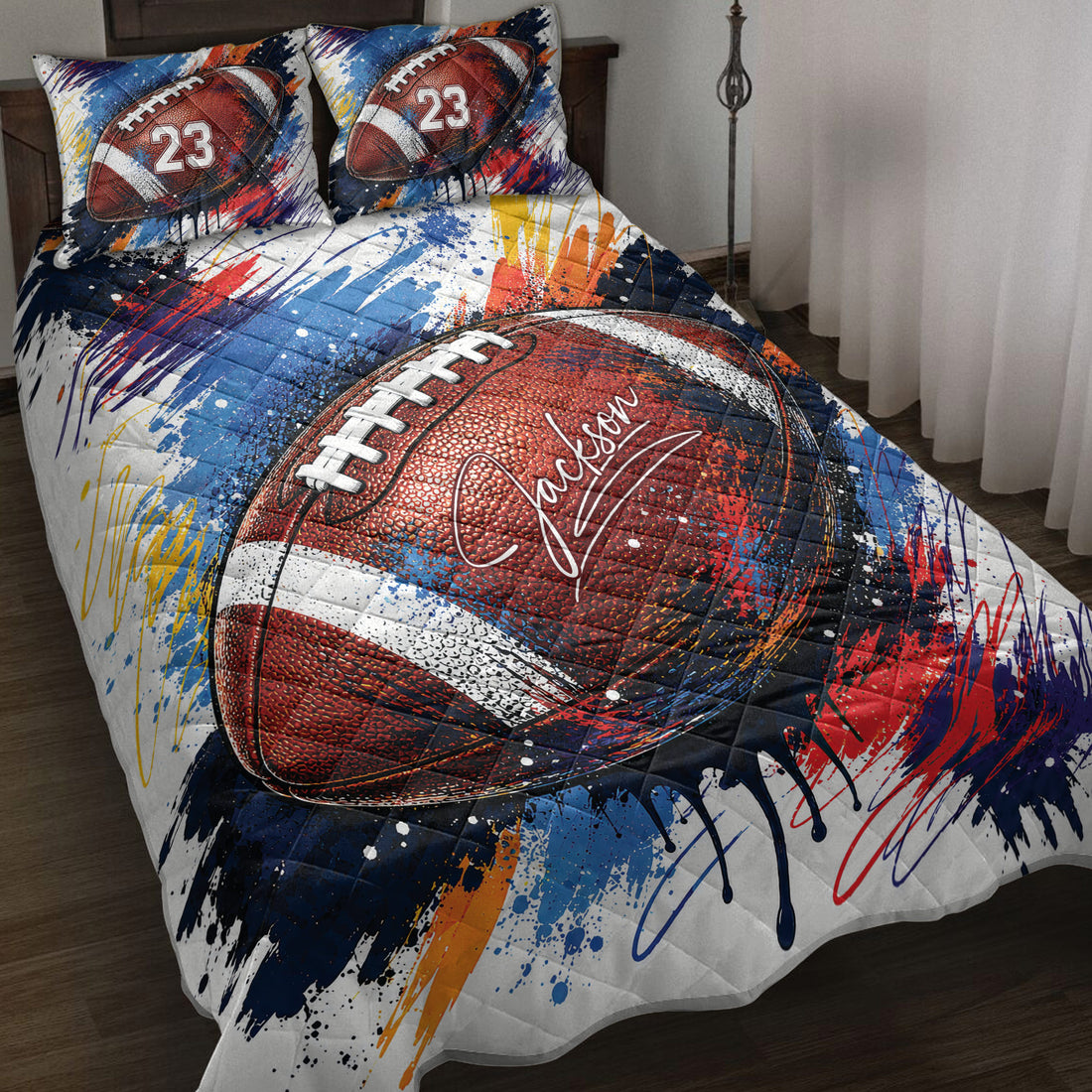 American football quilt blanket spread across a bed with bold red, blue, white and orange paint-splatter artwork