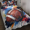 American football quilt blanket spread across a bed with bold red, blue, white and orange paint-splatter artwork