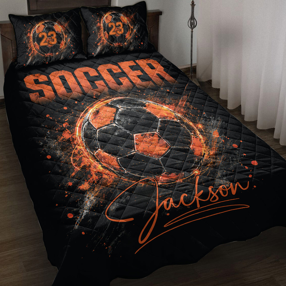Black and orange soccer quilt blanket displayed on a bed with fiery soccer ball artwork