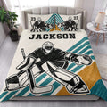 Hockey goalie quilt blanket styled on a bedroom bed with bold teal, white, and gold stripes