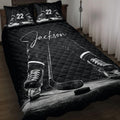 Black hockey quilt blanket displayed on a bed with skates, sticks, puck and dramatic ice artwork