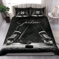 Hockey quilt blanket styled on a bedroom bed with black ice hockey skates and stick design