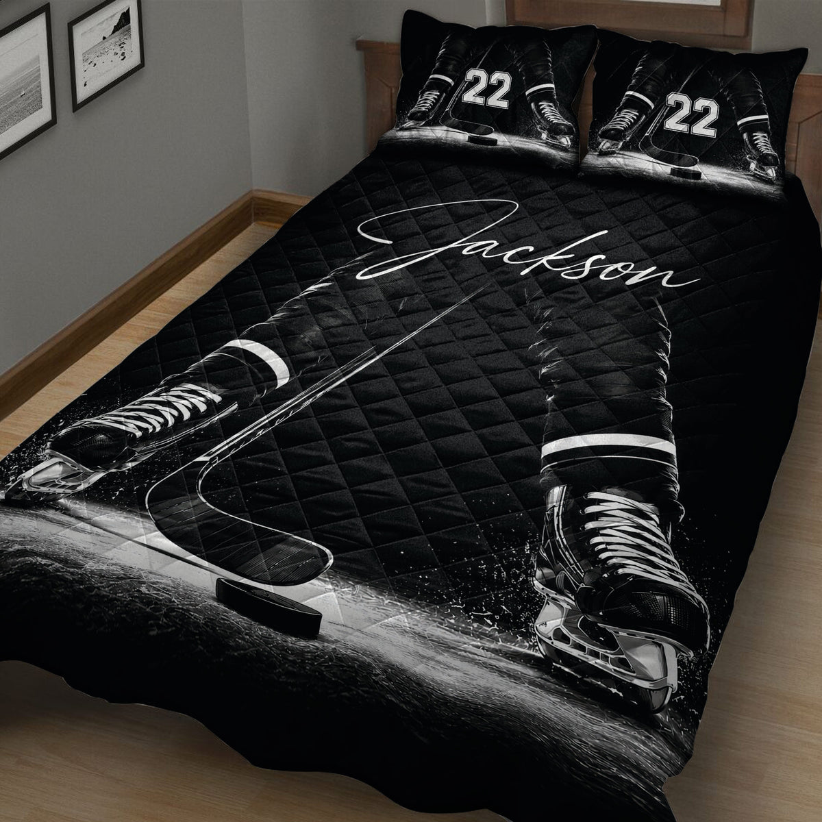 Close bedroom view of a black hockey quilt blanket with skates, sticks, puck and ice details