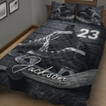Close bedroom view of a dark hockey quilt blanket featuring skates, pucks, and bold grayscale artwork