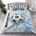 Soccer quilt blanket styled on a bedroom bed with blue and white soccer ball artwork