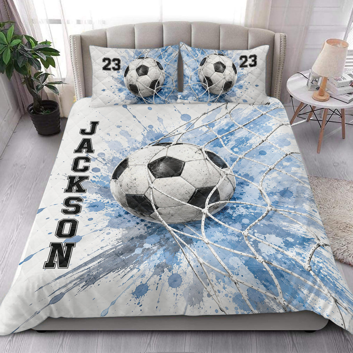 Soccer quilt blanket styled on a bedroom bed with blue and white soccer ball artwork