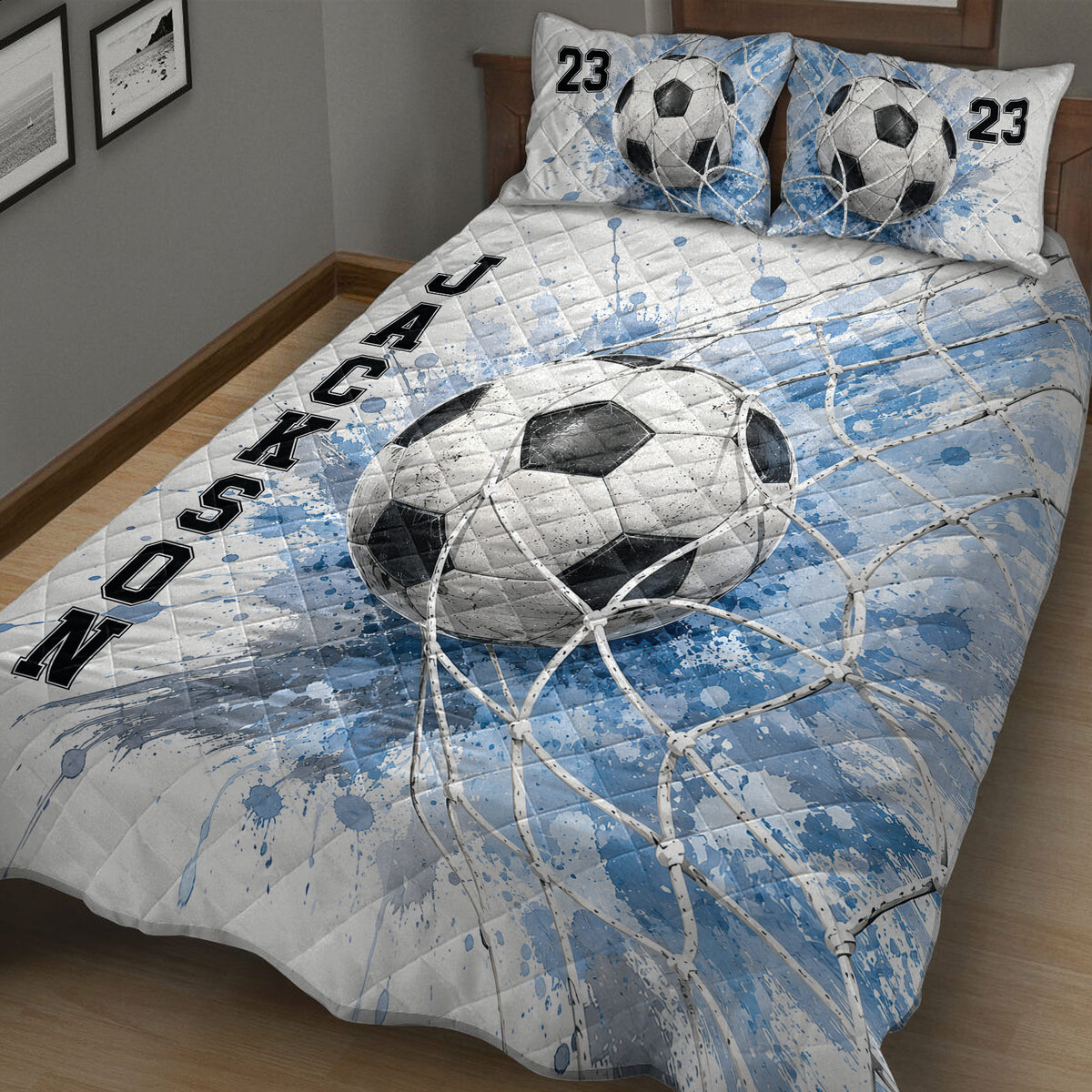 Close bedroom view of a soccer quilt blanket featuring a large ball and blue goal-net artwork