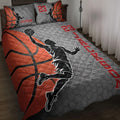 Basketball quilt blanket displayed on a bed with orange basketballs, player silhouettes, and red accents