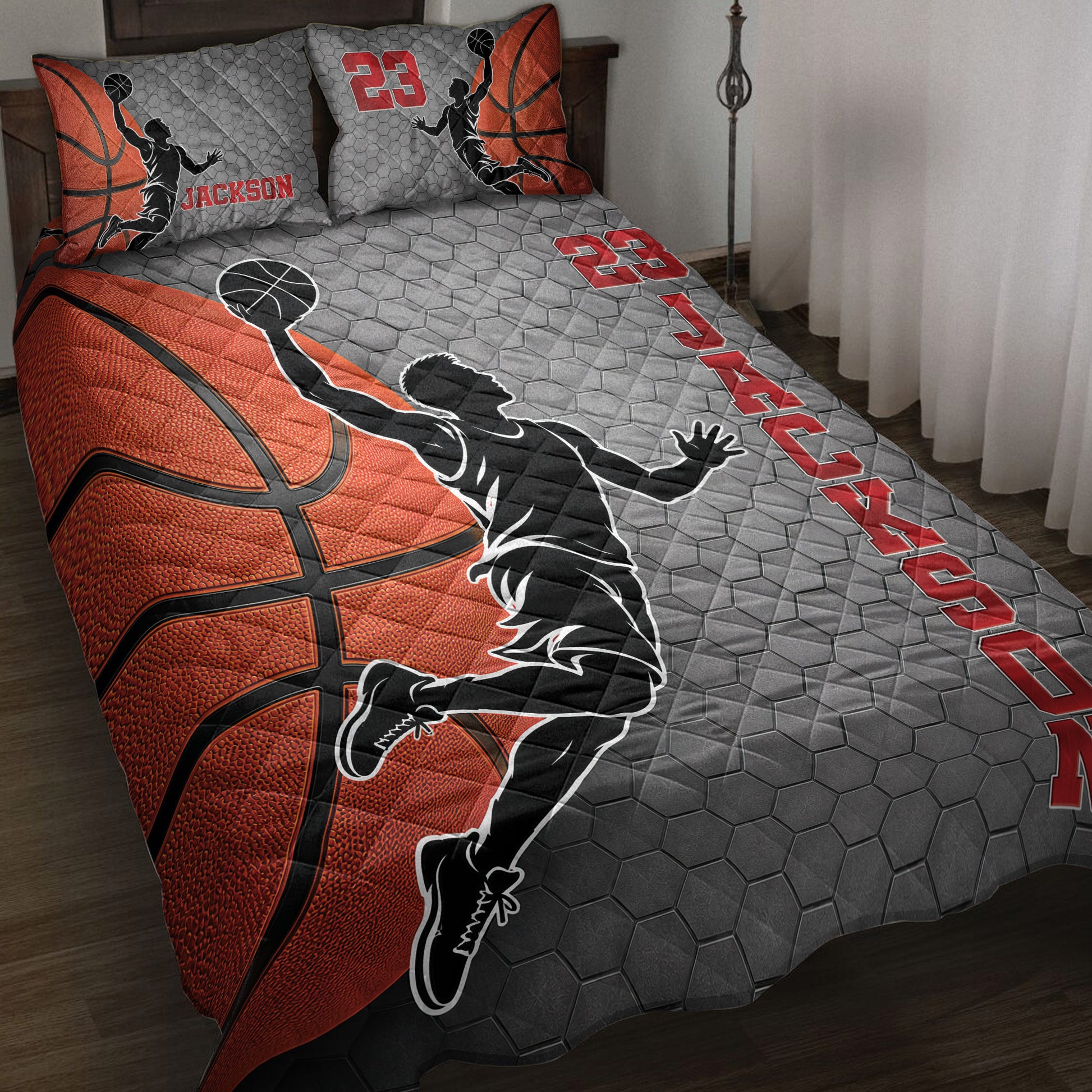 Basketball quilt blanket displayed on a bed with orange basketballs, player silhouettes, and red accents