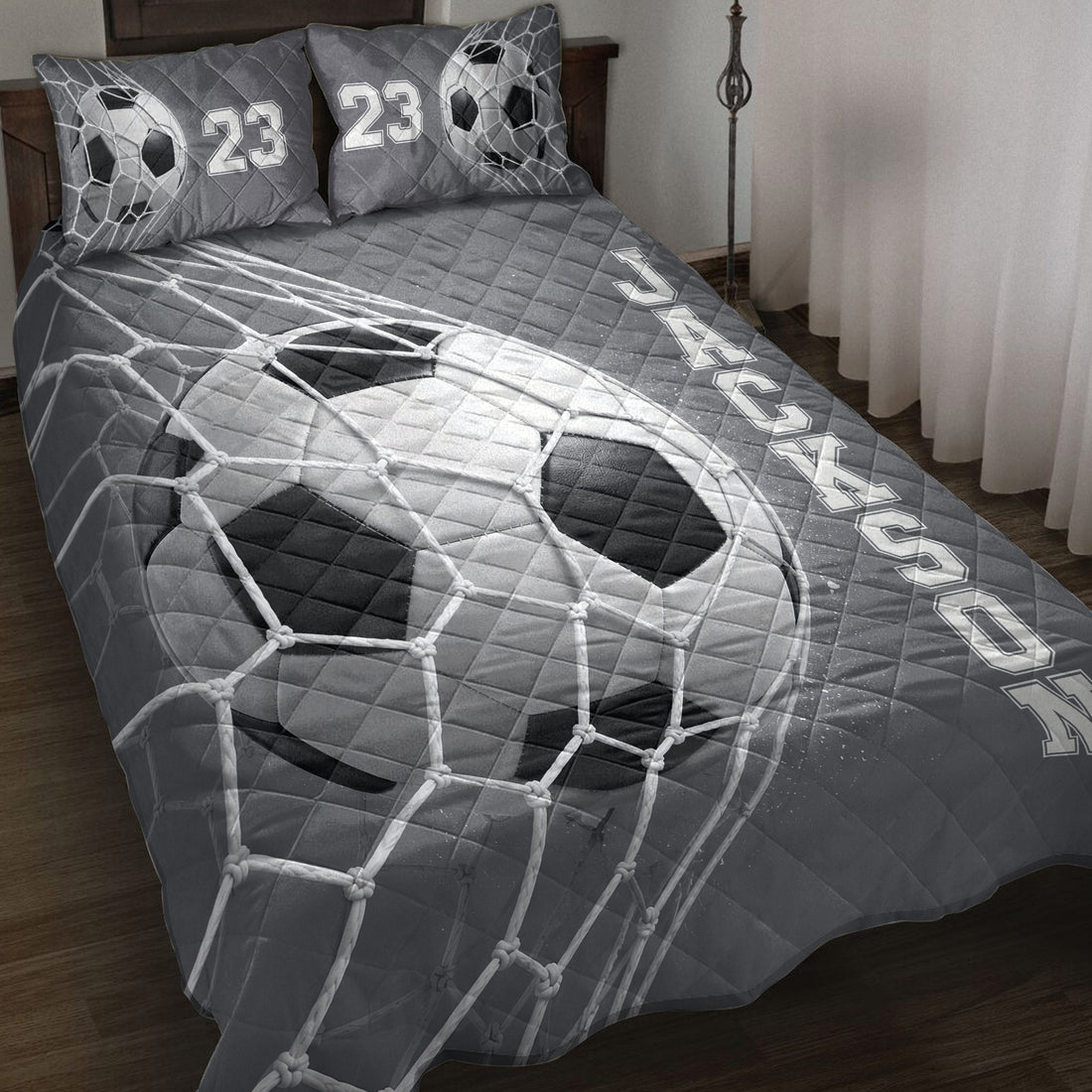Soccer quilt blanket spread across a bed with goal net and soccer ball artwork in charcoal gray