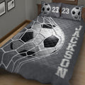 Close angled view of a charcoal soccer quilt blanket with oversized ball and net design