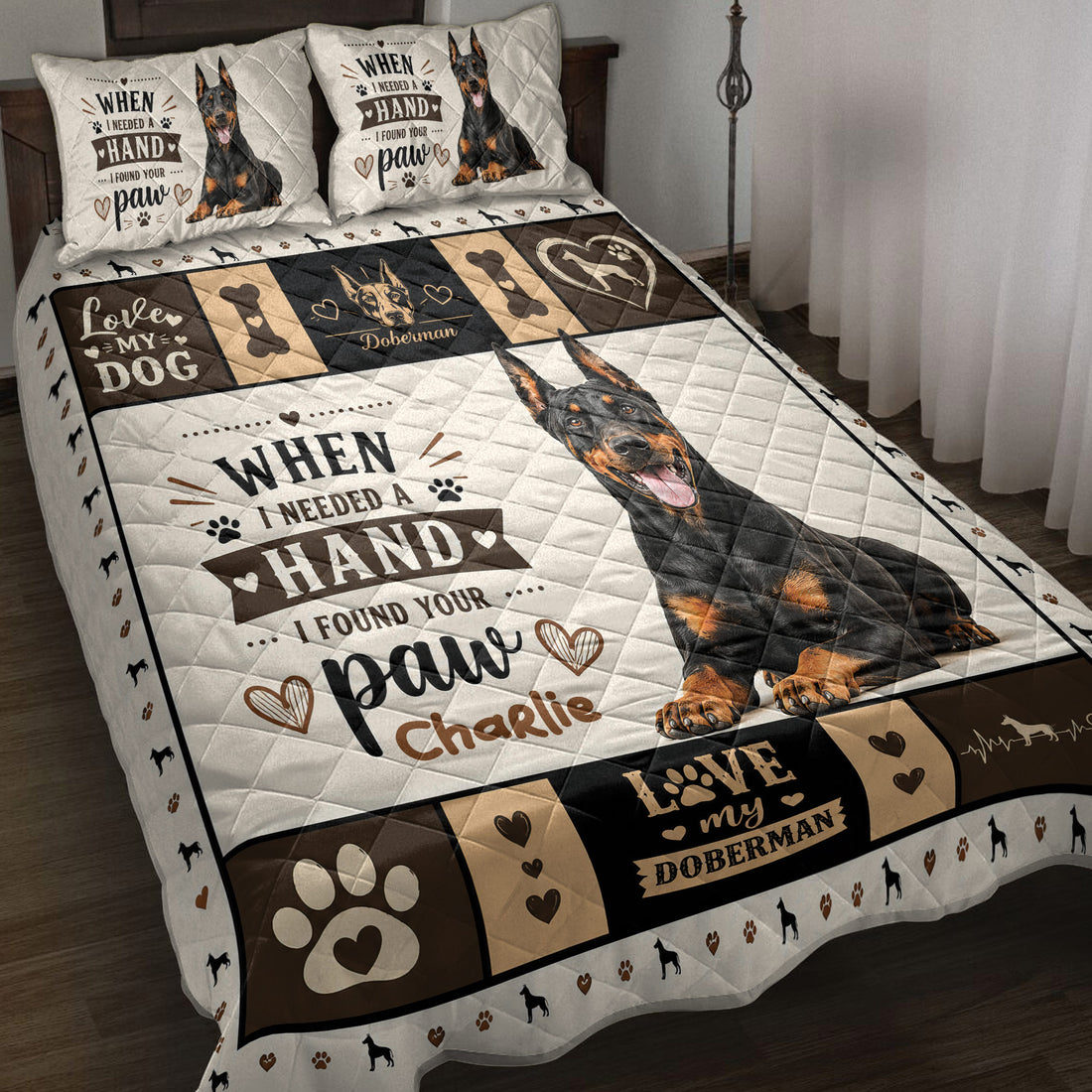 Doberman quilt blanket displayed on a bed with black, tan, cream, paw print, heart, and bone artwork