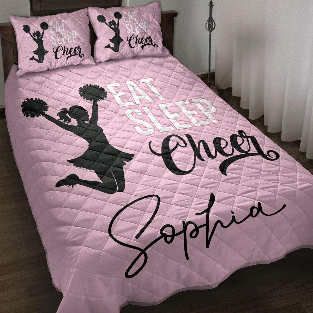 Pink cheerleading quilt blanket displayed on a bed with pom-pom cheerleader silhouettes and bold cheer artwork