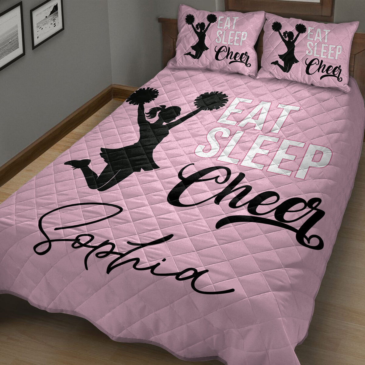 Pink cheerleading quilt blanket in a cozy bedroom featuring black pom-pom cheerleader artwork