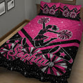 Pink cheerleading quilt blanket displayed on a bed with pom-poms, megaphones, stars, and cheerleader artwork