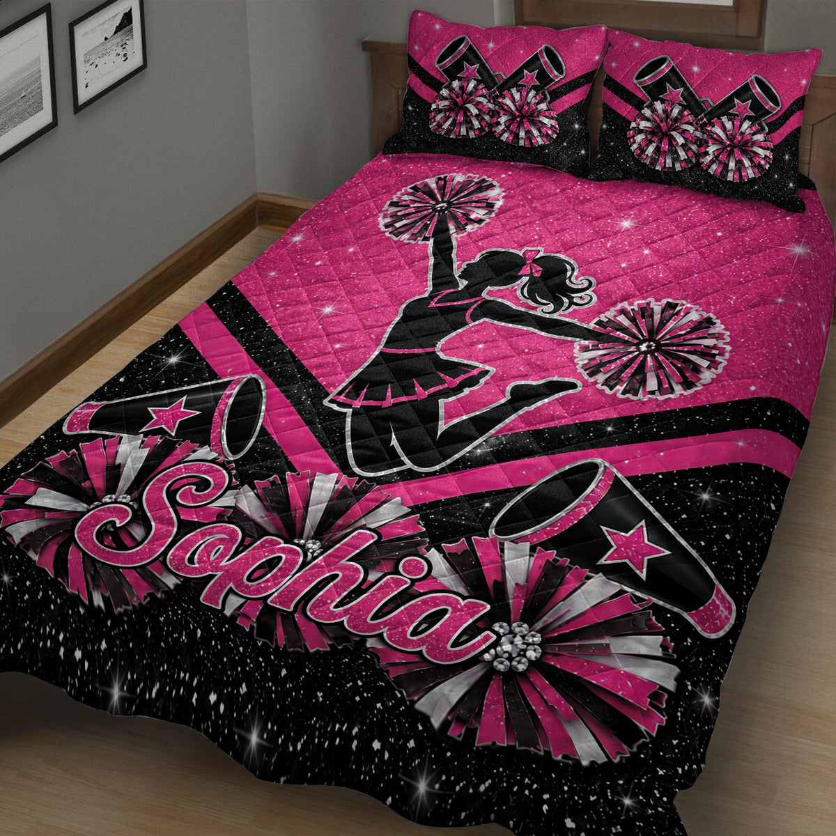 Pink cheerleading quilt blanket displayed on a bed with pom-poms, megaphones, stars, and cheerleader artwork