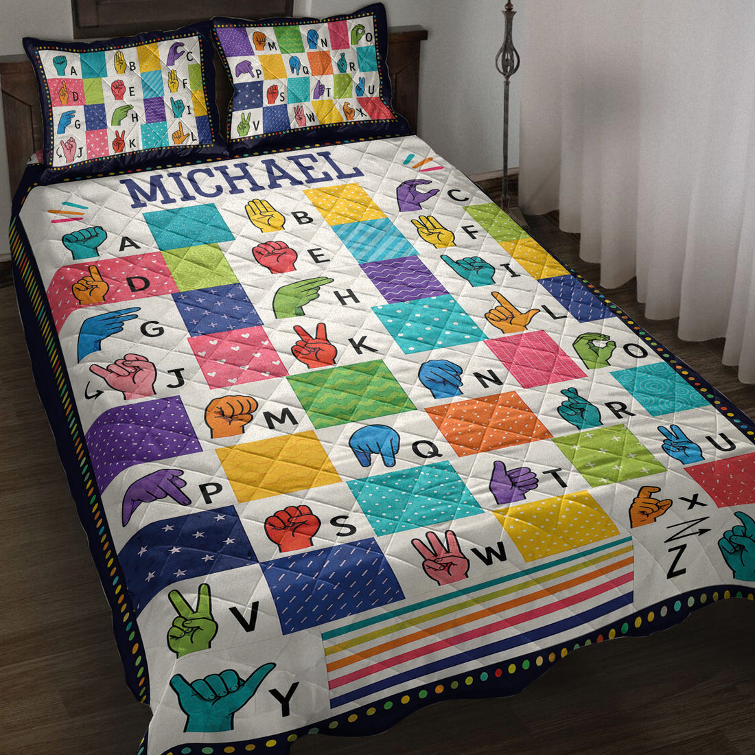 Colorful sign language alphabet quilt blanket styled on a bed with coordinating hand sign pillow designs