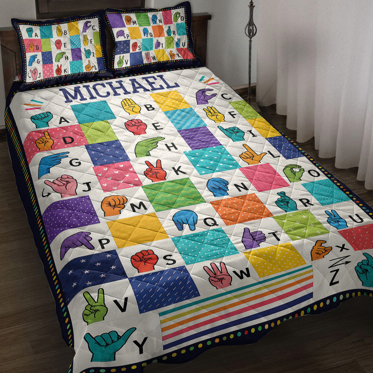 Colorful sign language alphabet quilt blanket styled on a bed with coordinating hand sign pillow designs