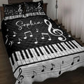 Black and white piano quilt blanket displayed on a bed with musical notes, treble clefs, and keyboard artwork