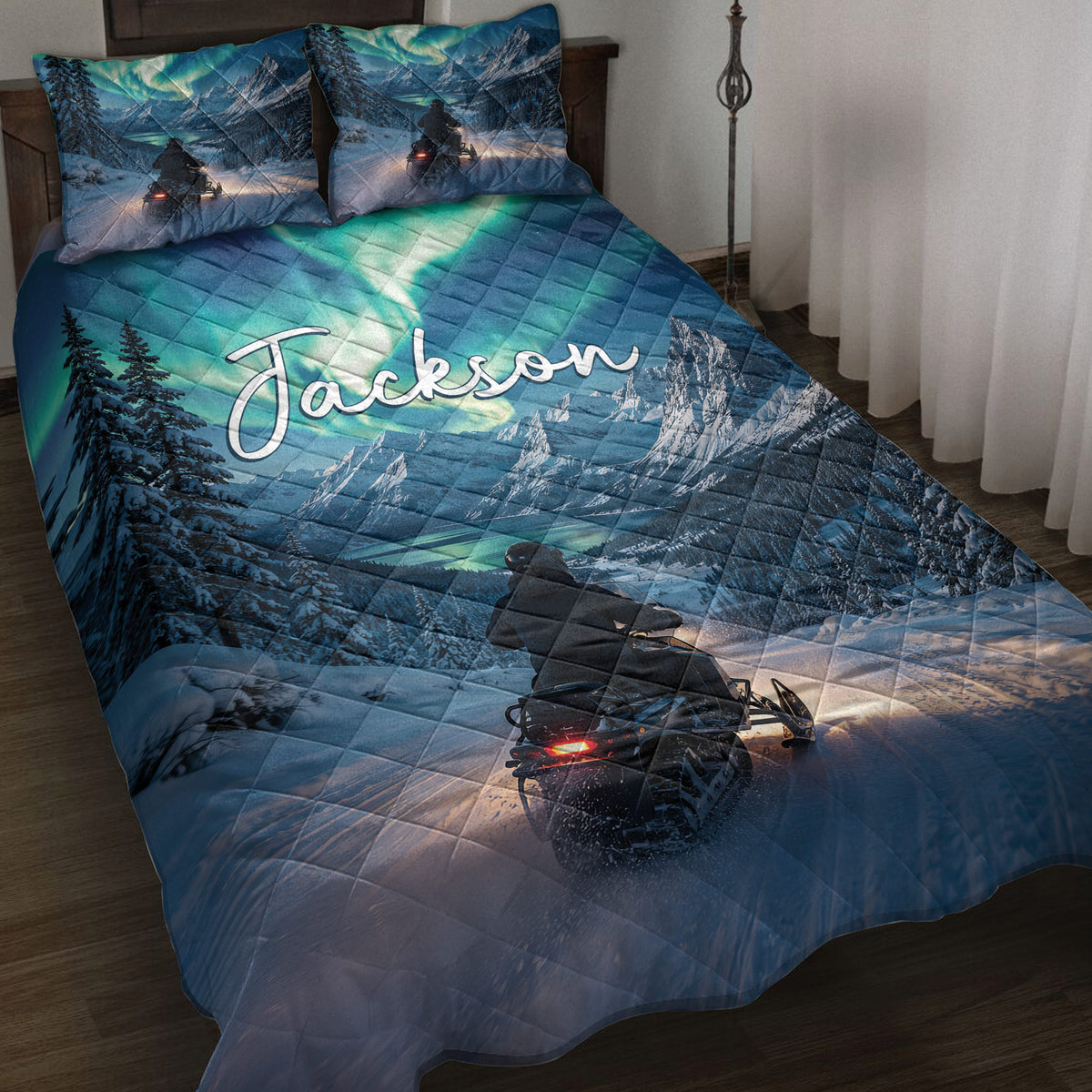 Snowmobile quilt blanket on a bed with snowy mountains, evergreen trees, aurora colors, and winter riding artwork