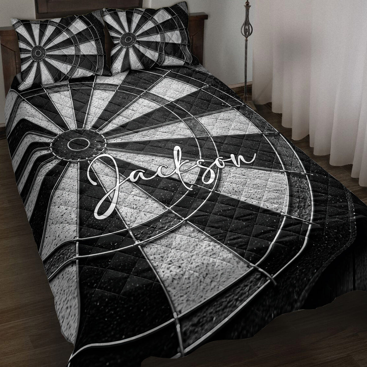 Black and white dartboard quilt blanket styled on a bedroom bed with matching dartboard pillows