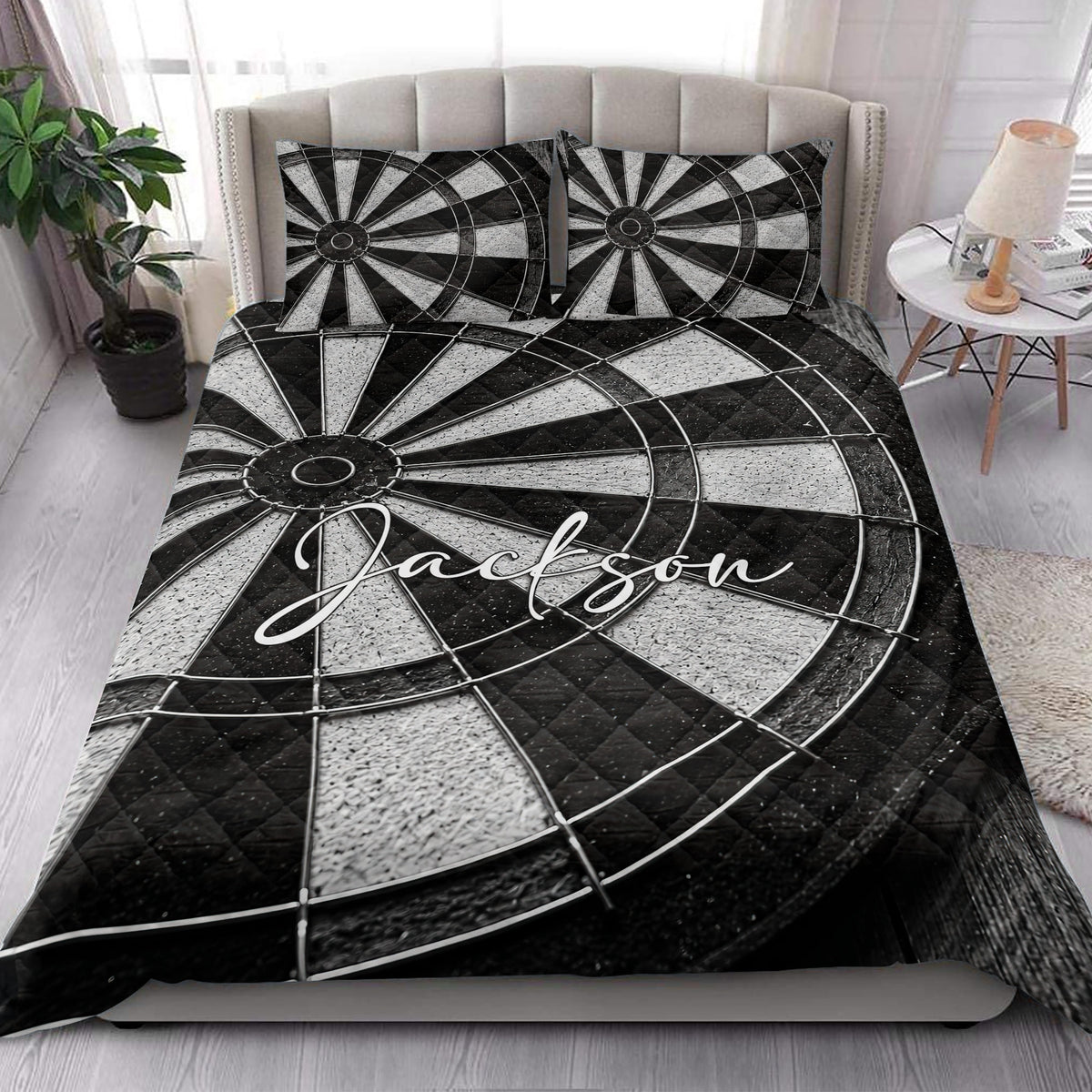 Dartboard quilt blanket displayed on a bright bedroom bed with matching black and white pillows