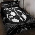 Black soccer quilt blanket displayed on a bed with bold white ball, goal, and stadium artwork