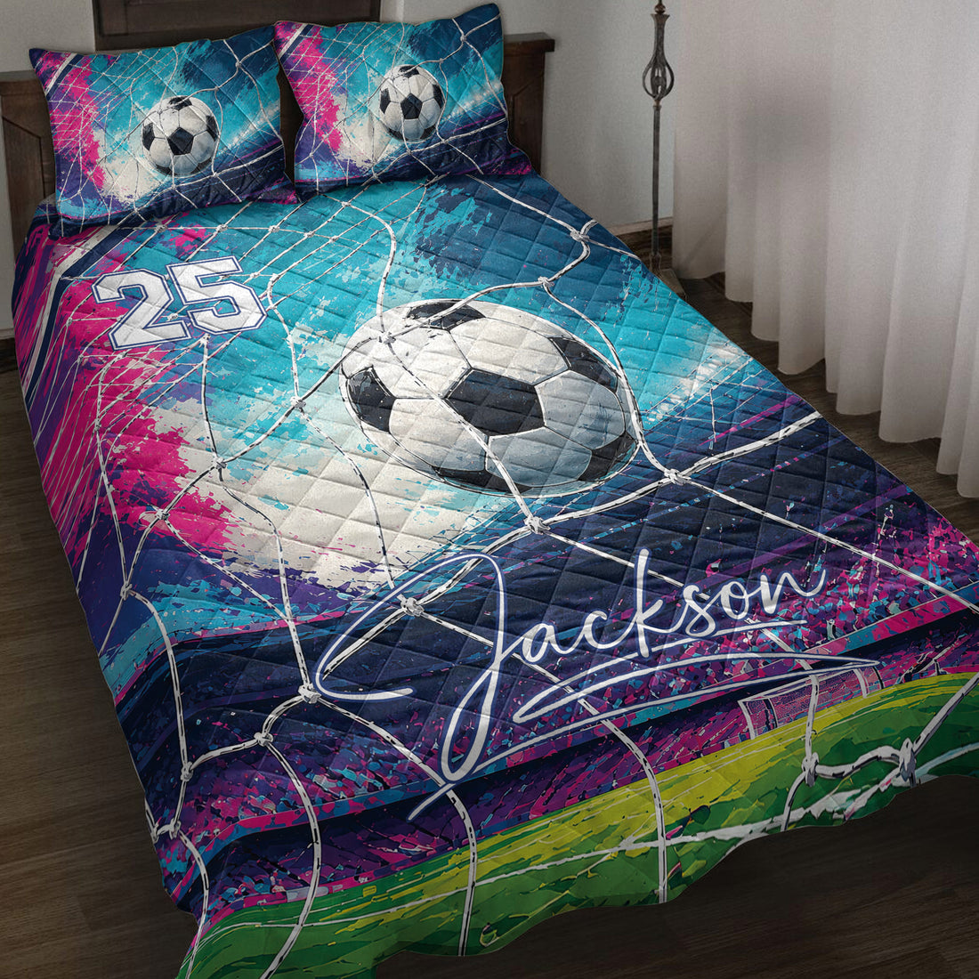 Soccer quilt blanket displayed on a bed with colorful goal-net artwork, soccer balls, and vibrant blue and pink accents