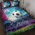 Soccer quilt blanket displayed on a bed with colorful goal-net artwork, soccer balls, and vibrant blue and pink accents