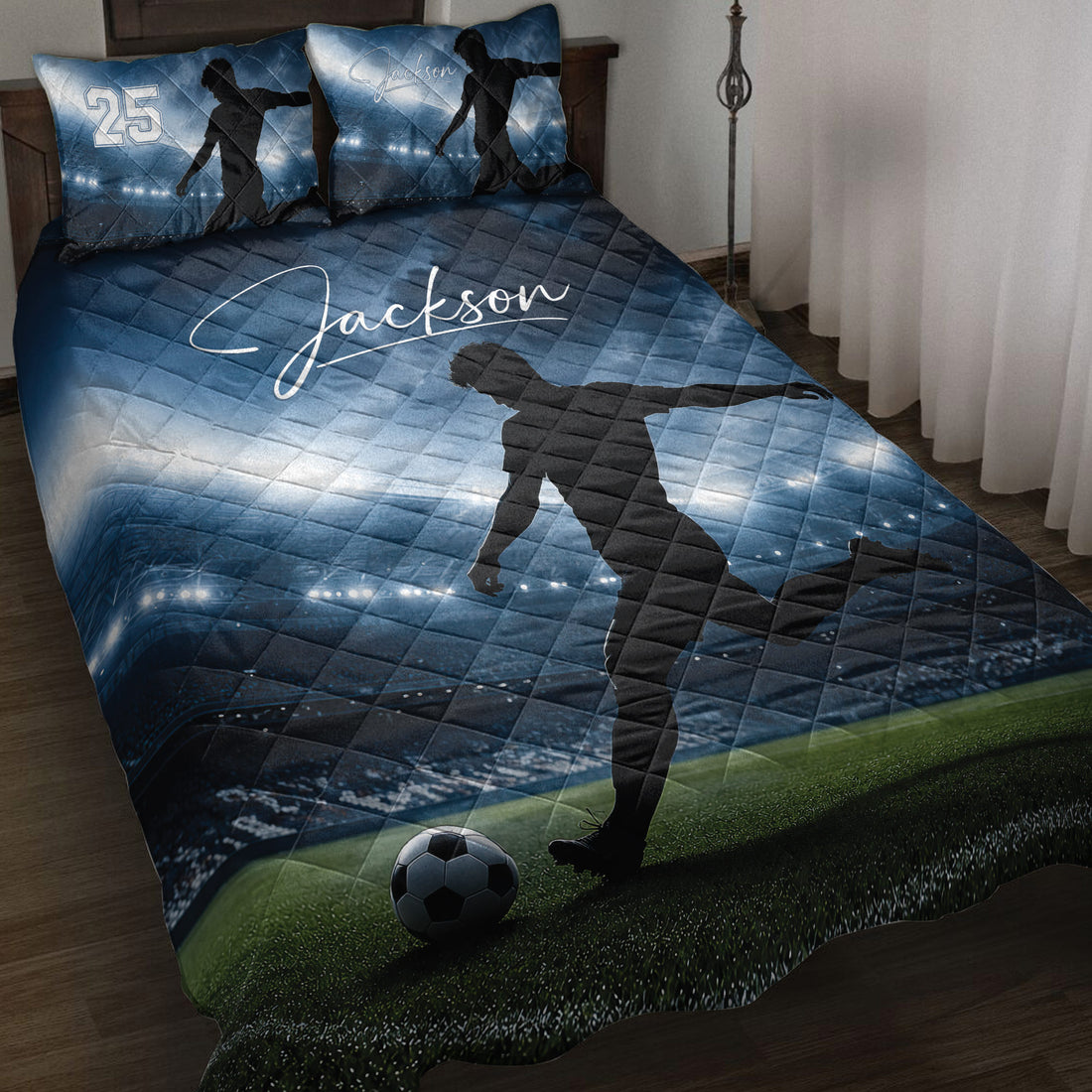 Blue soccer quilt blanket displayed on a bed with player silhouettes and stadium field artwork