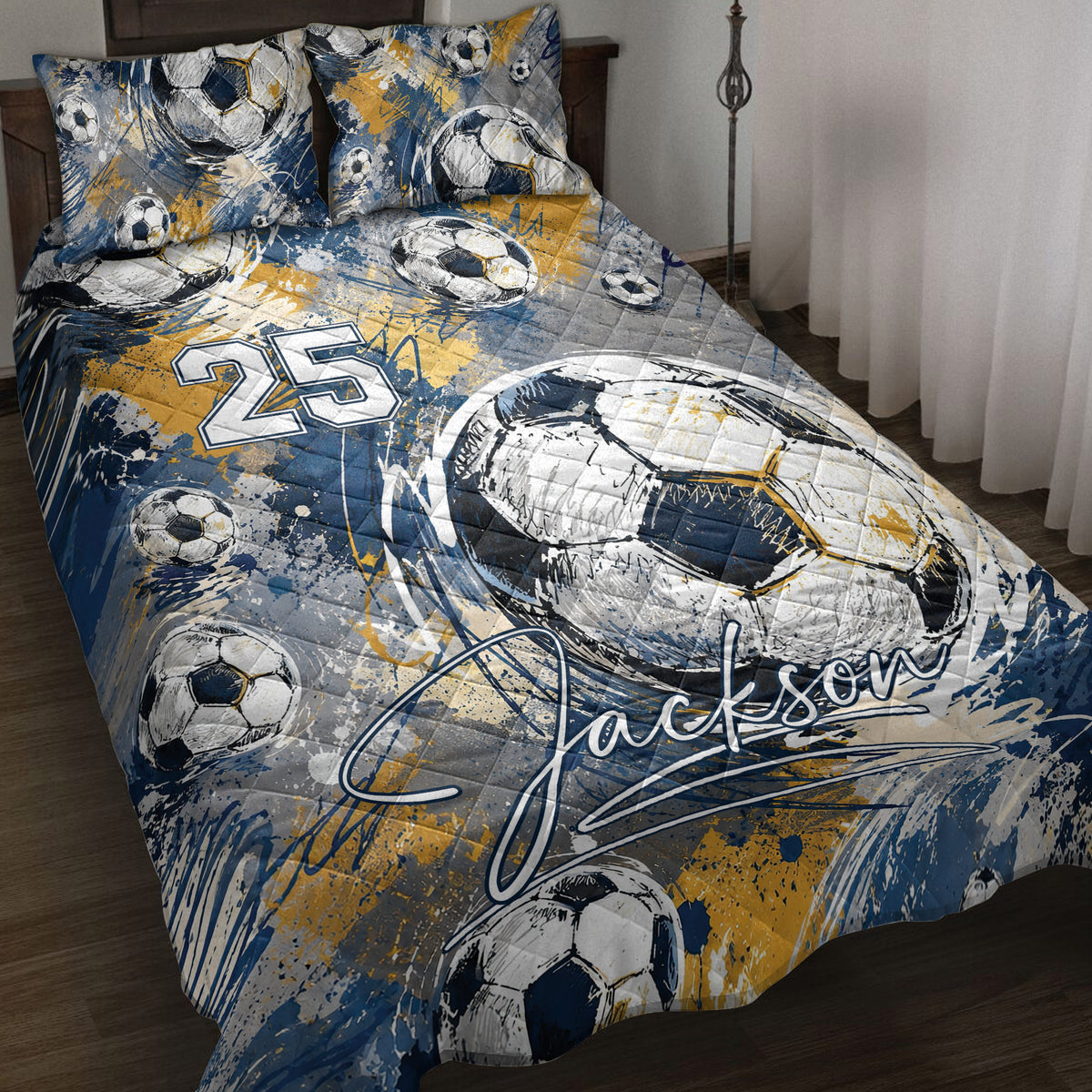 Soccer quilt blanket displayed on a bed with blue, gold, white, and gray ball artwork