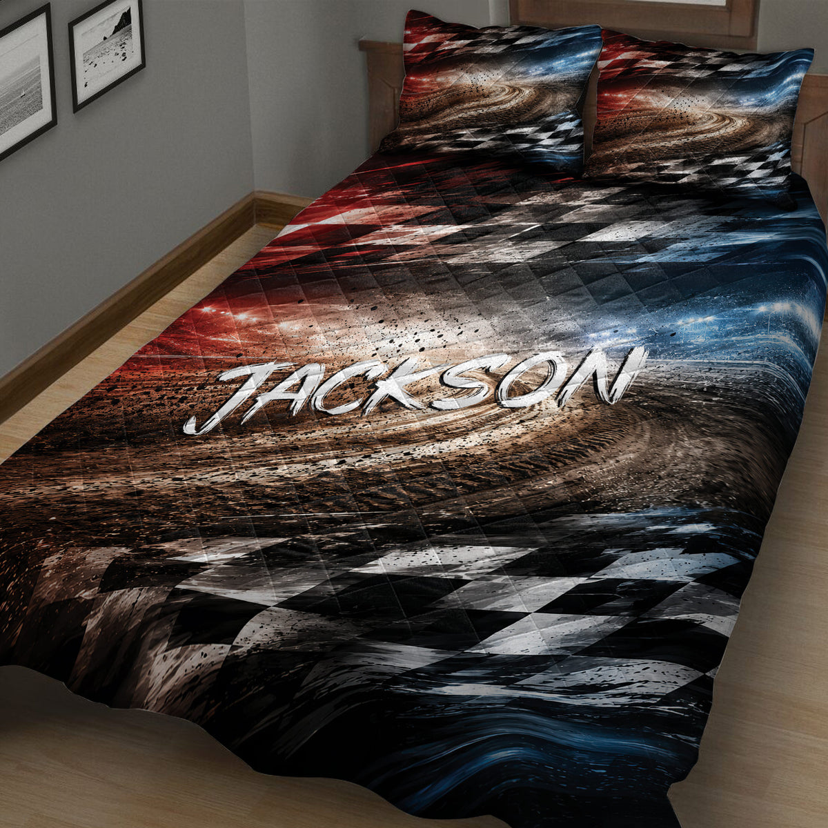 Close bedroom view of a racing quilt blanket featuring a sweeping track, checkered flags, and red, black, and blue accents