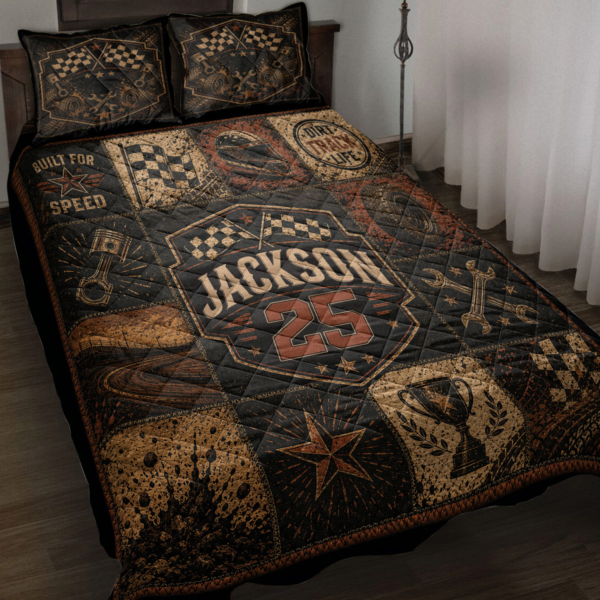 Dirt track racing quilt blanket displayed on a bed with checkered flags, racing helmet, tires and vintage motorsport artwork