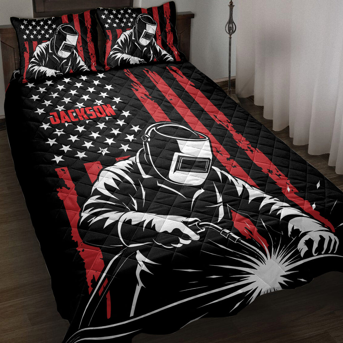 Welder quilt blanket displayed on a bed with black, red and white stars-and-stripes artwork