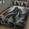 Close bedroom view of a Bigfoot quilt blanket with grayscale wilderness and waterfall artwork