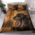 Cowboy quilt blanket styled on a bedroom bed with Western boots, hats, rope, and rustic wood artwork