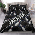 Bowling quilt blanket styled on a bedroom bed with black bowling balls and white pins