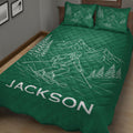Green ski quilt blanket displayed in a bedroom with skier, mountain, and evergreen artwork